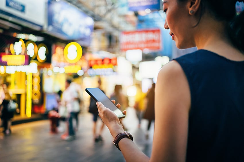 Frau mit Telefon, die vor Geschäften steht